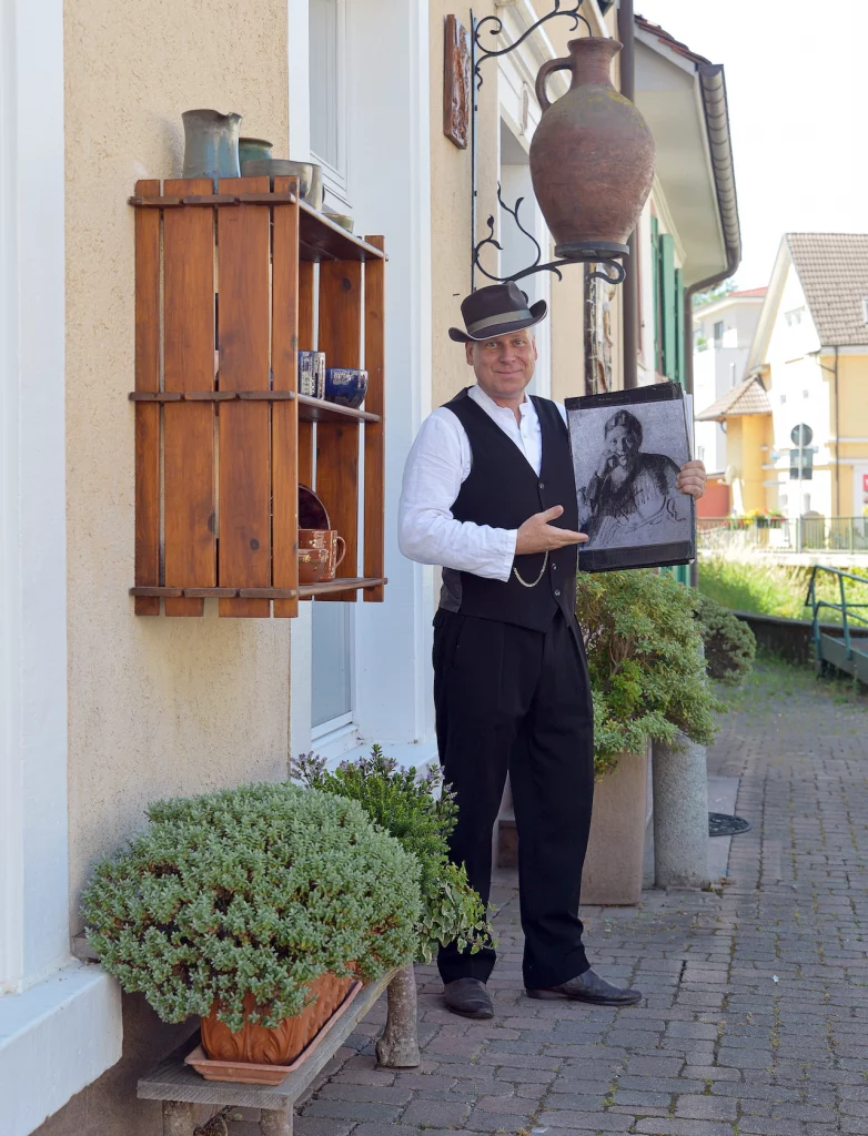 Wigand Neumann in der Rolle des Malers August Macke bei einer schauspielerischen Stadtfuehrung durch Kandern steht an einem Hauseingang und zeigt eine Zeichnung von sich