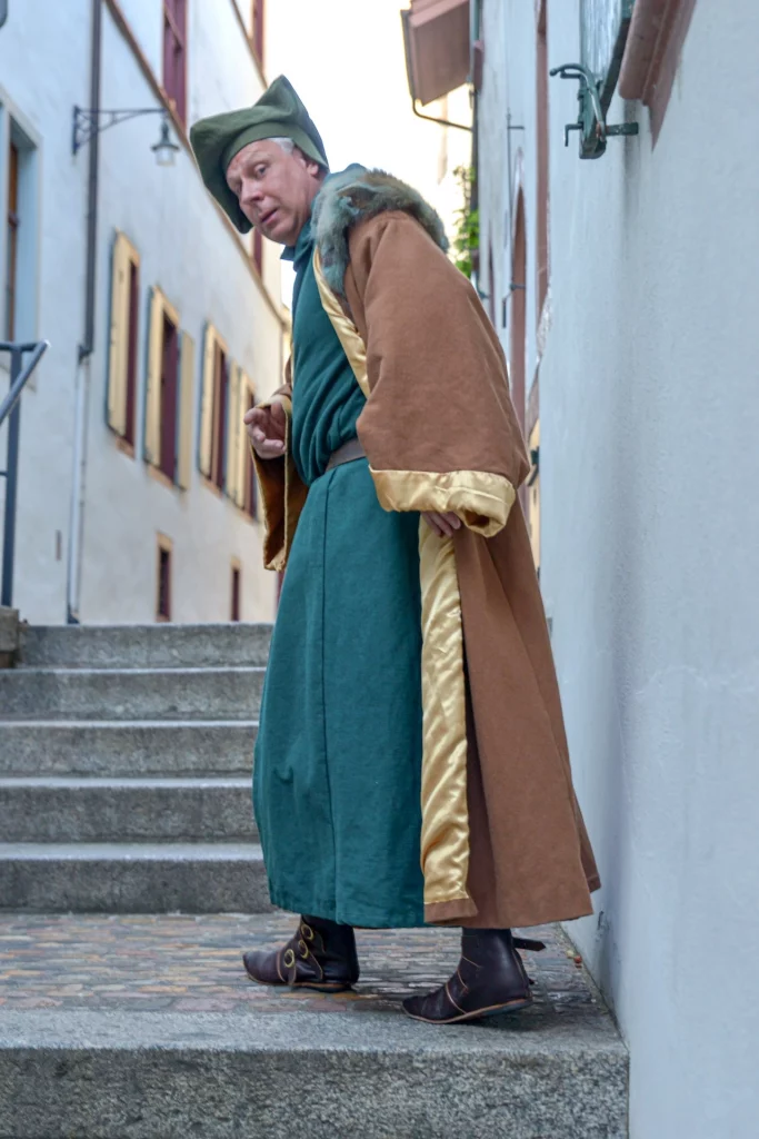 Wigand Neumann in der Rolle des Erasmus von Rotterdam bei einer schauspielerischen Stadtfuehrung in der Altstadt von Basel die Treppe hochlaufend