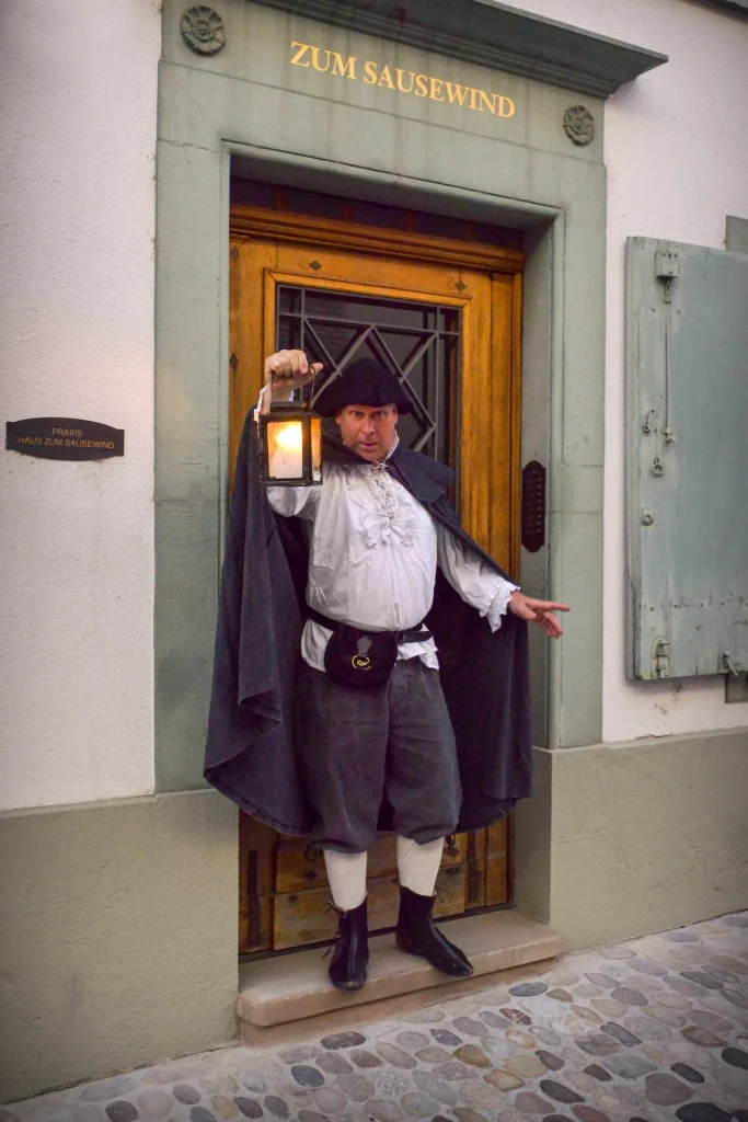 Wigand Neumann in der Rolle des Nachtwaechters bei einer naechtlichen schauspielerischen Stadtfuehrung im St. Alban Tal in Basel haelt eine Laterne
