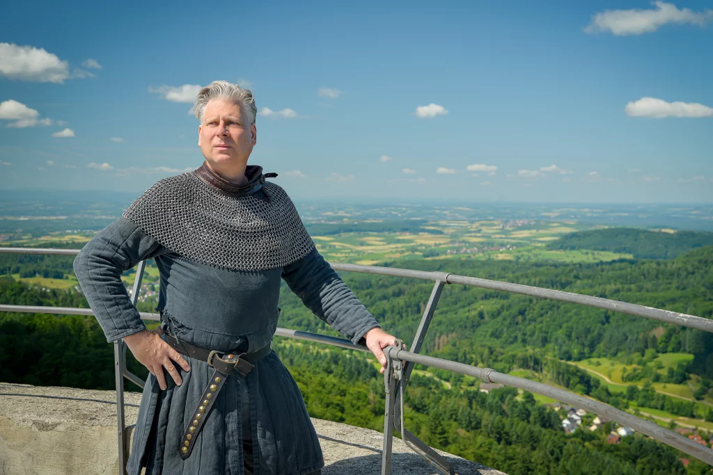 Wigand Neumann in der Rolle des Ritters Markgraf Wilhelm bei einer Schauspielfuehrung auf der Sausenburg mit Blick aufs Markgraeflerland im Hintegrund