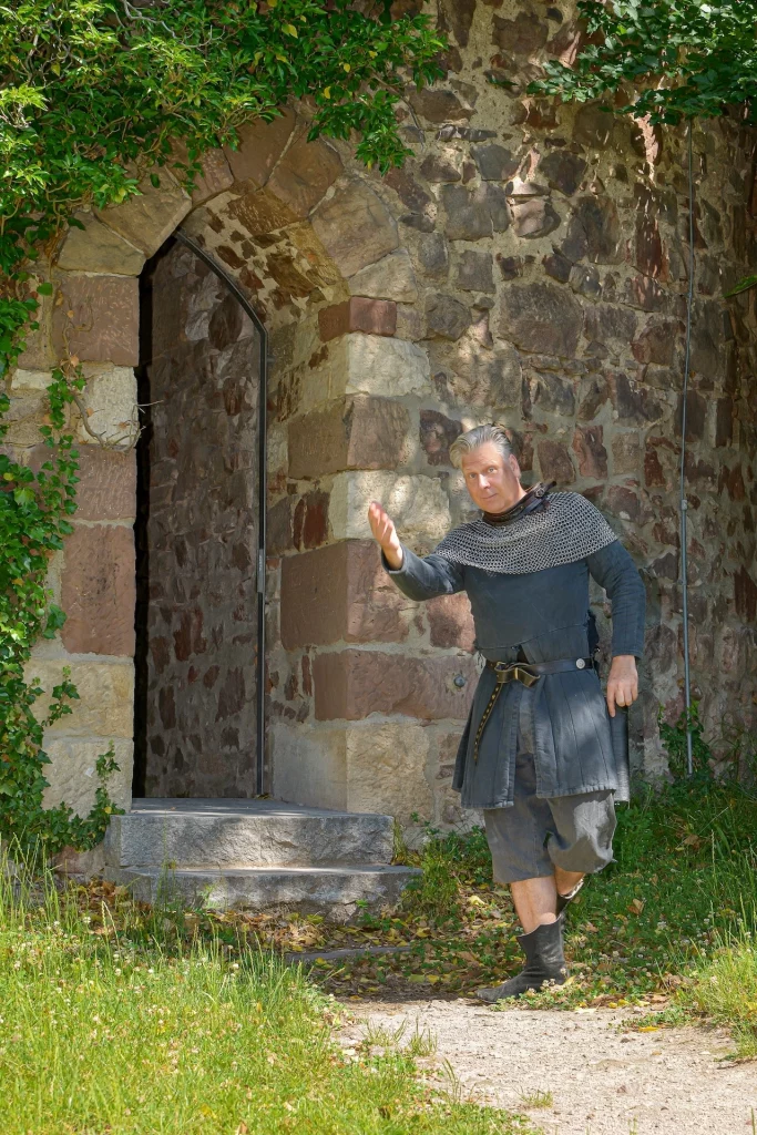 Wigand Neumann in der Rolle des Ritters Markgraf Wilhelm bei einer Schauspielfuehrung bei einer einladenden Geste auf die Sausenburg